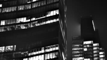 Pattern of office buildings windows illuminated at night. Glass architecture ,corporate building at night - business concept. Black and white. photo