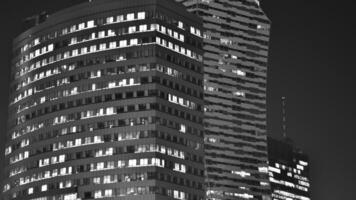 Pattern of office buildings windows illuminated at night. Glass architecture ,corporate building at night - business concept. Black and white. photo