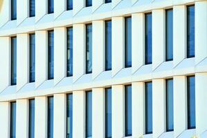 Abstract closeup of the glass-clad facade of a modern building covered in reflective plate glass. Architecture abstract background. Glass wall and facade detail. photo