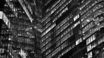 Pattern of office buildings windows illuminated at night. Glass architecture ,corporate building at night - business concept. Black and white. photo