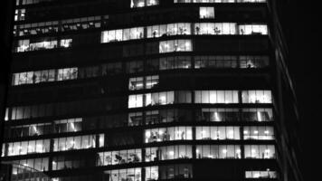 Pattern of office buildings windows illuminated at night. Glass architecture ,corporate building at night - business concept. Black and white. photo