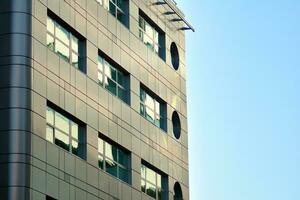 Abstract closeup of the glass-clad facade of a modern building covered in reflective plate glass. Architecture abstract background. Glass wall and facade detail. photo