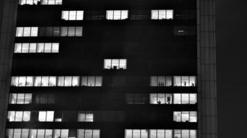 Pattern of office buildings windows illuminated at night. Glass architecture ,corporate building at night - business concept. Black and white. photo