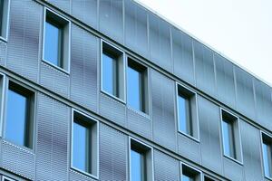 Abstract closeup of the glass-clad facade of a modern building covered in reflective plate glass. Architecture abstract background. Glass wall and facade detail. photo