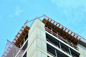 High rise building under construction. Installation of glass facade panels on a reinforced concrete structure. photo