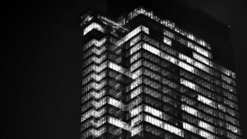 Pattern of office buildings windows illuminated at night. Glass architecture ,corporate building at night - business concept. Black and white. photo