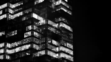 Pattern of office buildings windows illuminated at night. Glass architecture ,corporate building at night - business concept. Black and white. photo