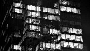 Pattern of office buildings windows illuminated at night. Glass architecture ,corporate building at night - business concept. Black and white. photo