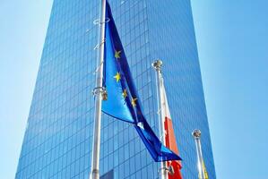 Flaga Unii Europejskiej i polska flaga na tle nowoczesnego budynku. photo
