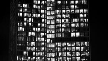 Pattern of office buildings windows illuminated at night. Glass architecture ,corporate building at night - business concept. Black and white. photo