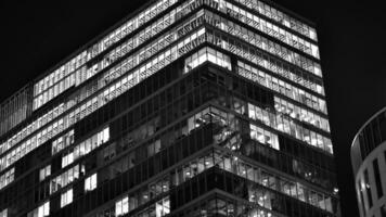 Pattern of office buildings windows illuminated at night. Glass architecture ,corporate building at night - business concept. Black and white. photo