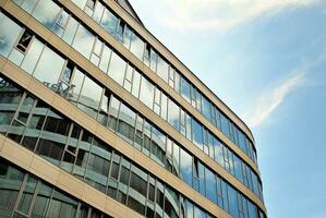 Abstract closeup of the glass-clad facade of a modern building covered in reflective plate glass. Architecture abstract background. Glass wall and facade detail. photo