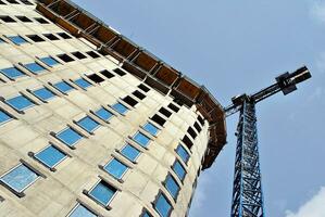 High rise building under construction. Installation of glass facade panels on a reinforced concrete structure. photo