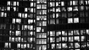 Pattern of office buildings windows illuminated at night. Glass architecture ,corporate building at night - business concept. Black and white. photo