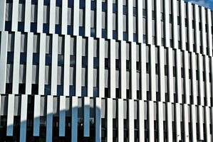 Abstract closeup of the glass-clad facade of a modern building covered in reflective plate glass. Architecture abstract background. Glass wall and facade detail. photo