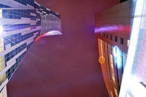 fragmento de el vaso fachada de un moderno corporativo edificio a noche. moderno vaso oficina en ciudad. grande brillante ventanas en moderno oficina edificios a noche, en filas de ventanas ligero brilla foto