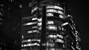 Pattern of office buildings windows illuminated at night. Glass architecture ,corporate building at night - business concept. Black and white. photo