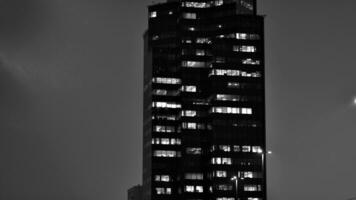 Pattern of office buildings windows illuminated at night. Glass architecture ,corporate building at night - business concept. Black and white. photo