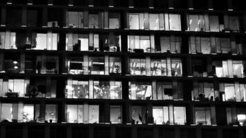 Pattern of office buildings windows illuminated at night. Glass architecture ,corporate building at night - business concept. Black and white. photo