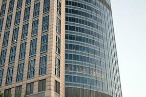 Abstract closeup of the glass-clad facade of a modern building covered in reflective plate glass. Architecture abstract background. Glass wall and facade detail. photo