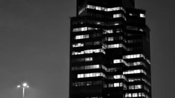 Pattern of office buildings windows illuminated at night. Glass architecture ,corporate building at night - business concept. Black and white. photo