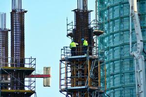 High rise building under construction. Installation of glass facade panels on a reinforced concrete structure. photo