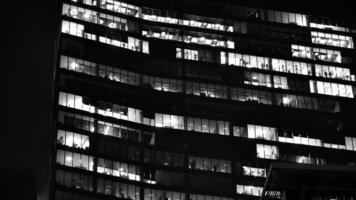 Pattern of office buildings windows illuminated at night. Glass architecture ,corporate building at night - business concept. Black and white. photo