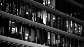 Pattern of office buildings windows illuminated at night. Glass architecture ,corporate building at night - business concept. Black and white. photo