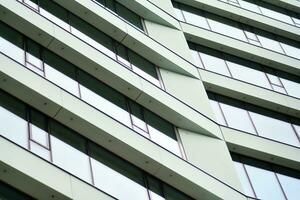 Abstract closeup of the glass-clad facade of a modern building covered in reflective plate glass. Architecture abstract background. Glass wall and facade detail. photo