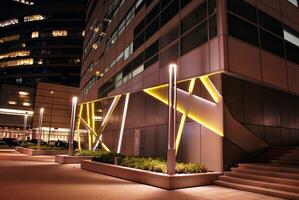 Fragment of the glass facade of a modern corporate building at night. Modern glass office  in city. Big glowing windows in modern office buildings at night, in rows of windows light shines. photo