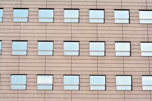 Abstract closeup of the glass-clad facade of a modern building covered in reflective plate glass. Architecture abstract background. Glass wall and facade detail. photo