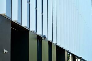 Abstract closeup of the glass-clad facade of a modern building covered in reflective plate glass. Architecture abstract background. Glass wall and facade detail. photo