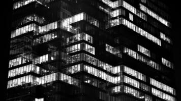 Pattern of office buildings windows illuminated at night. Glass architecture ,corporate building at night - business concept. Black and white. photo