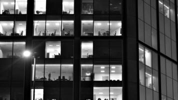 Pattern of office buildings windows illuminated at night. Glass architecture ,corporate building at night - business concept. Black and white. photo