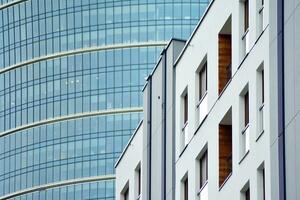 Abstract closeup of the glass-clad facade of a modern building covered in reflective plate glass. Architecture abstract background. Glass wall and facade detail. photo