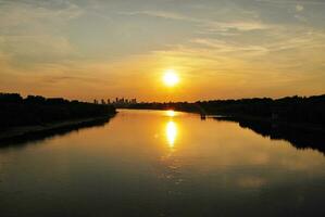 River in the city in at colorful sunset in the background photo