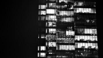 Pattern of office buildings windows illuminated at night. Glass architecture ,corporate building at night - business concept. Black and white. photo