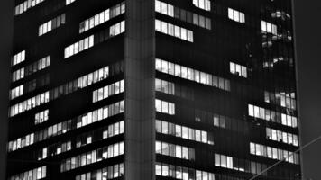 Pattern of office buildings windows illuminated at night. Glass architecture ,corporate building at night - business concept. Black and white. photo