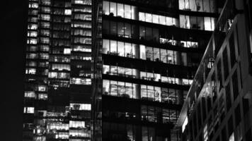 Pattern of office buildings windows illuminated at night. Glass architecture ,corporate building at night - business concept. Black and white. photo