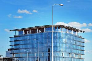 Glass building with transparent facade of the building and blue sky. Structural glass wall reflecting blue sky. Abstract modern architecture fragment. Contemporary architectural background. photo