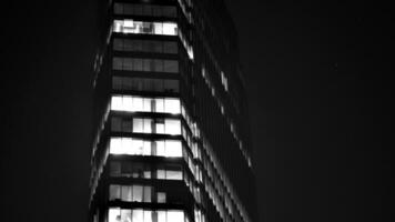 Pattern of office buildings windows illuminated at night. Glass architecture ,corporate building at night - business concept. Black and white. photo