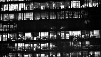 Pattern of office buildings windows illuminated at night. Glass architecture ,corporate building at night - business concept. Black and white. photo