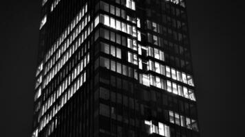 Pattern of office buildings windows illuminated at night. Glass architecture ,corporate building at night - business concept. Black and white. photo