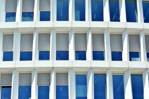 Abstract closeup of the glass-clad facade of a modern building covered in reflective plate glass. Architecture abstract background. Glass wall and facade detail. photo