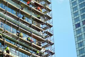 High rise building under construction. Installation of glass facade panels on a reinforced concrete structure. photo