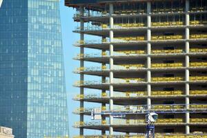 High rise building under construction. Installation of glass facade panels on a reinforced concrete structure. photo