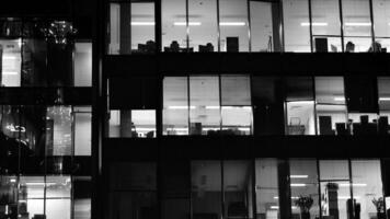 Pattern of office buildings windows illuminated at night. Glass architecture ,corporate building at night - business concept. Black and white. photo