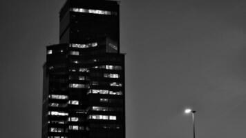 Pattern of office buildings windows illuminated at night. Glass architecture ,corporate building at night - business concept. Black and white. photo