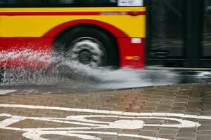 Splashes from under the wheels of the bus during heavy rain. Blurred bus. photo