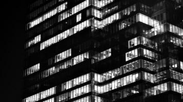 Pattern of office buildings windows illuminated at night. Glass architecture ,corporate building at night - business concept. Black and white. photo